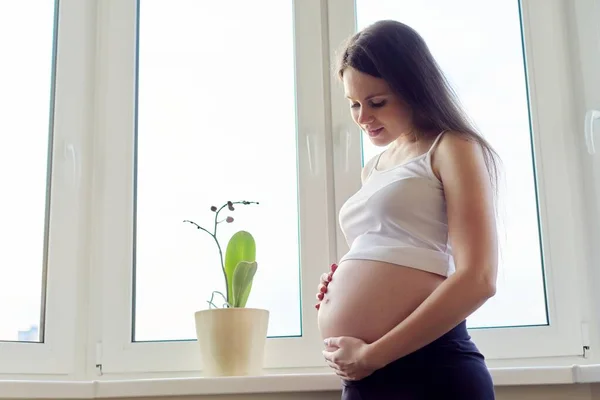 Young beautiful pregnant woman touching her belly with love — Stock Photo, Image