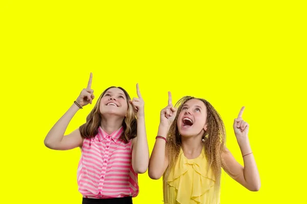 Dua gadis remaja emosional muncul dan melihat ke atas, menyalin ruang latar belakang kuning — Stok Foto