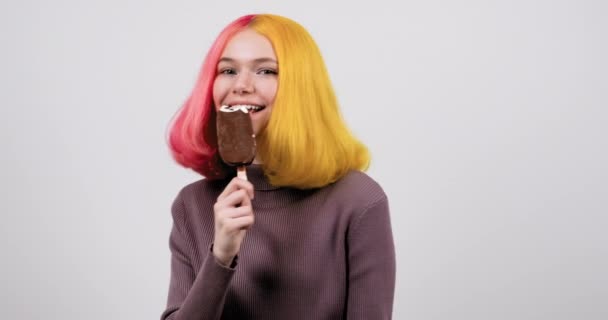 Joven modelo adolescente con helado de chocolate en la mano sobre fondo de estudio gris claro — Vídeos de Stock