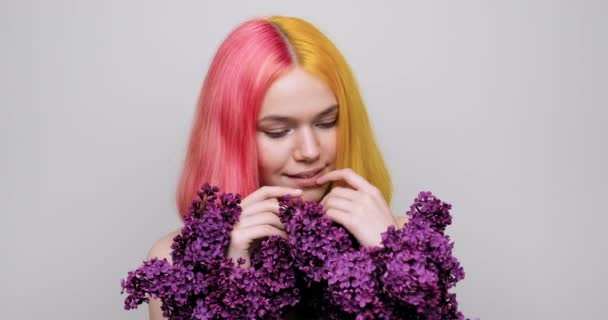 Tiener meisje met geverfd paars geel haar houden lila bloemen in handen — Stockvideo