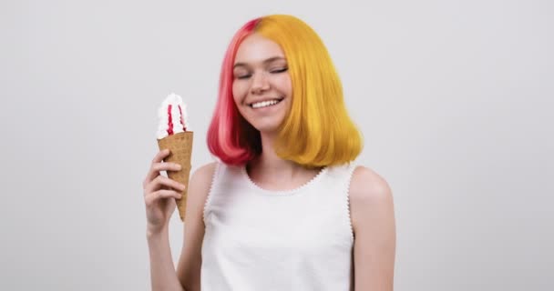 Adolescente modelo sonriente con helado en cono de gofre sobre fondo de estudio gris claro — Vídeos de Stock