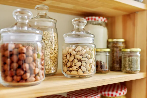 Kuchyňská spíž, dřevěné police se sklenicemi a nádobami s jídlem, sklad potravin. — Stock fotografie