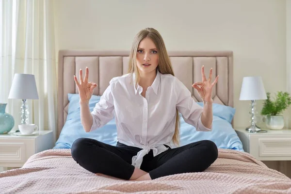 Yoga meditatie, jonge mooie blonde vrouw zittend in lotuspositie in bed — Stockfoto