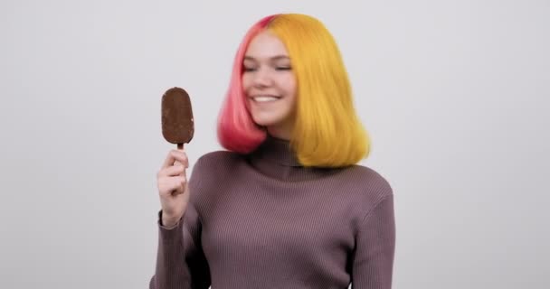 Jong model tiener met chocolade ijs in de hand op licht grijze studio achtergrond — Stockvideo