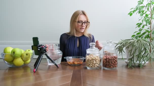 Aktivering av vitaminer i nötter. Kvinna nutritionist blötläggning nötter i vatten, konsultation online — Stockvideo