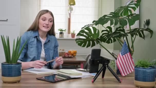 Молодая женщина студентка учится на дому дистанционно, США флаг фоне — стоковое видео