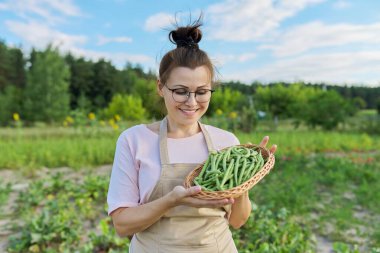 Gülen kadın çiftçi sepetinde taze yeşil fasulye hasadıyla
