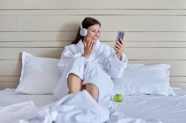 Video görüşmesi için akıllı telefon kullanan kulaklıklı olgun bir kadınla konuşmaktan mutluluk duyarım.