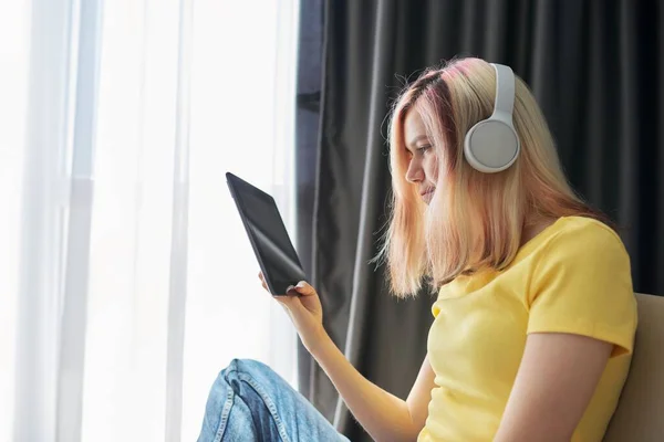 High school student teenager girl in headphones with tablet at home