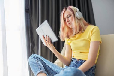Evde tabletle kulaklık takan liseli kız.