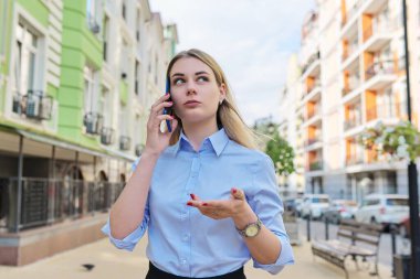 Genç ciddi bir iş kadını cep telefonuyla konuşuyor.