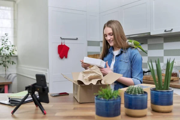 Karton kutuları açan akıllı telefondan video kaydeden bir kadın. Evcil papağan paketleri açmaya yardım ediyor — Stok fotoğraf