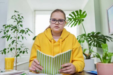 Ergenlik öncesi kız evde ders çalışıyor, liseli kız web kamerasına bakıyor.