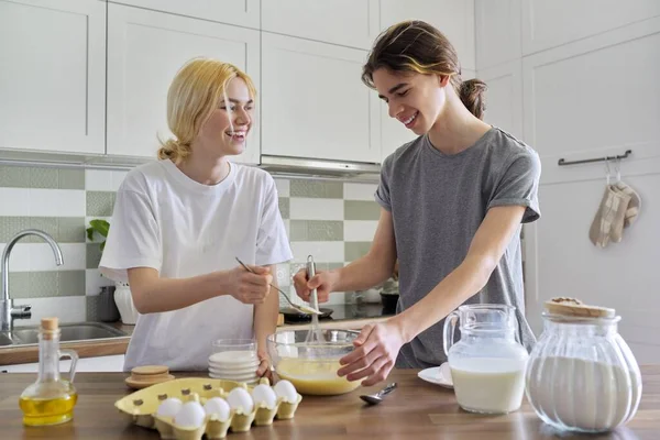 Adolescentes cara e menina cozinhar panquecas na cozinha juntos — Fotografia de Stock