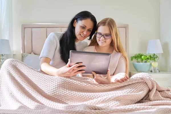 Feliz mamá y preadolescente hija abrazándose juntos mirando a la pantalla de la tableta digital — Foto de Stock