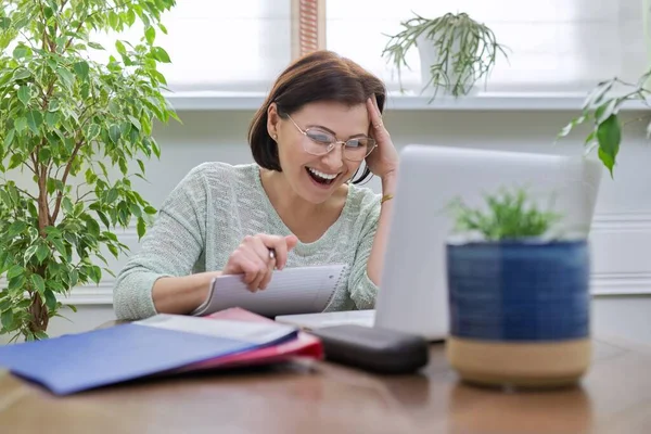 Жіночий вчитель викладає онлайн, сидячи вдома за столом з ноутбуком — стокове фото