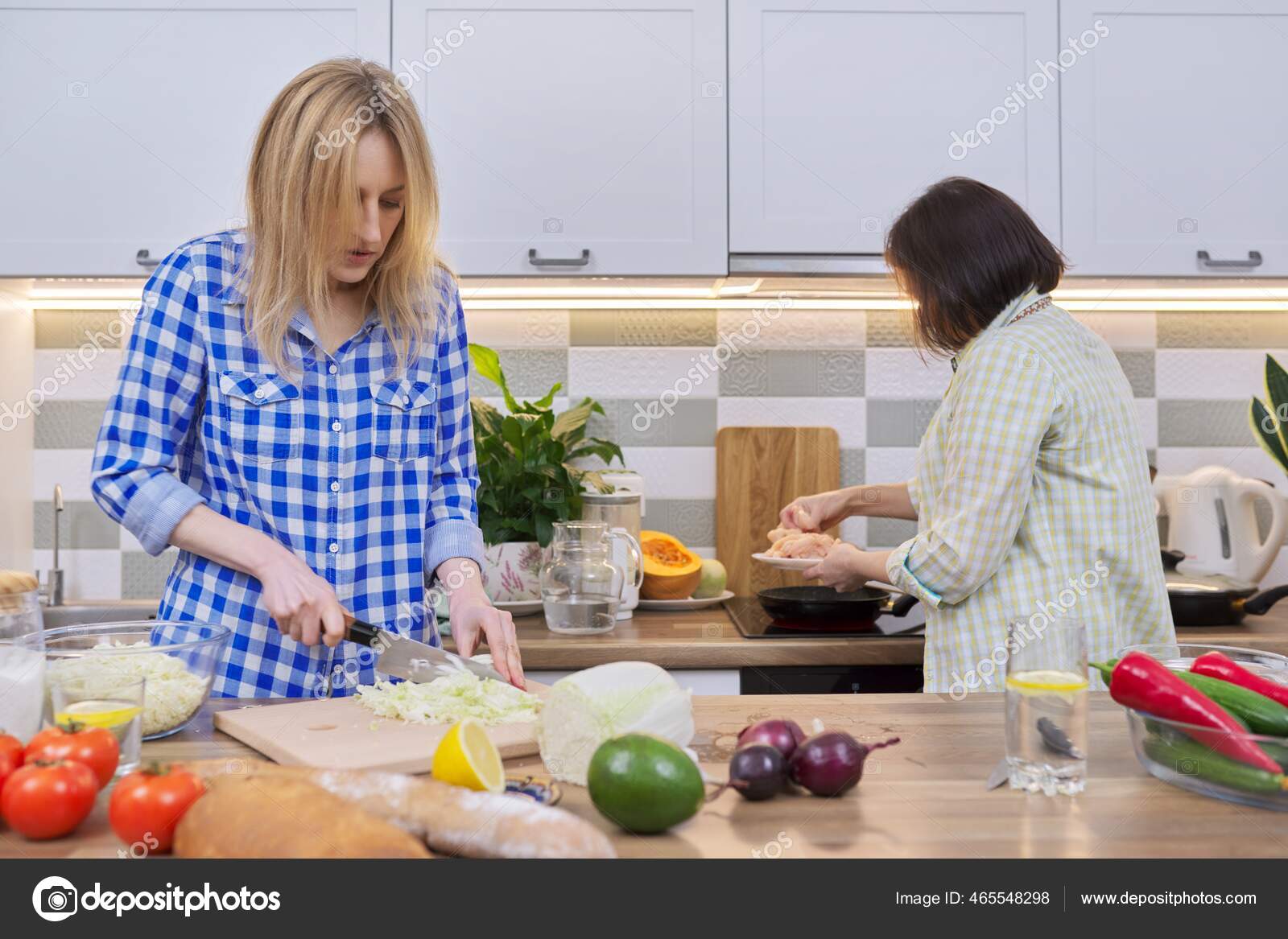 Two middle aged women cooking together at home in kitchen Stock Photo by ©Valerii_Honcharuk 465548298