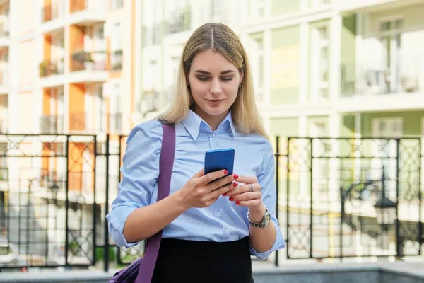 Молодая деловая женщина со смартфоном, на заднем плане здания уличного офиса — стоковое фото