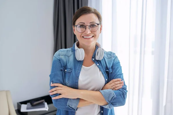 Portrait de femme mature d'âge moyen confiante portant des lunettes et des écouteurs — Photo