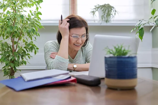 Зріла жінка працює в домашньому офісі за допомогою ноутбука — стокове фото