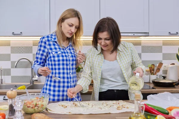 Due donne di mezza età cucinano insieme a casa in cucina — Foto Stock