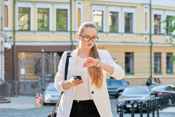 Молодая деловая женщина в городе смотрит на свои наручные часы — стоковое фото