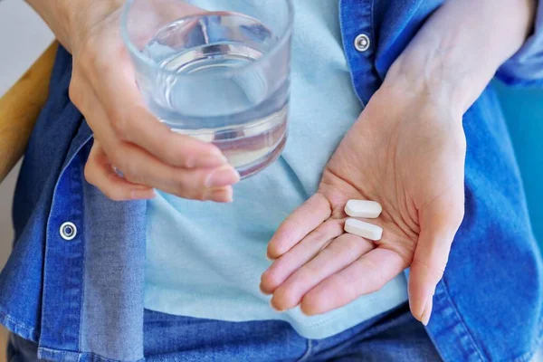 Nahaufnahme von reifen Frauen Hand mit Tabletten und Glas Wasser — Stockfoto