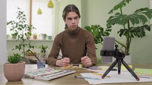 Adolescente chico dibujo con acuarelas, viendo vídeo clase en el teléfono inteligente — Vídeo de stock