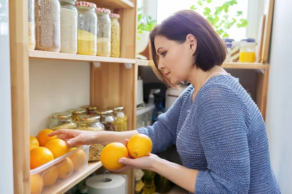 Inicio despensa cocina interior, mujer sosteniendo naranjas en las manos, almacenamiento de alimentos — Foto de Stock