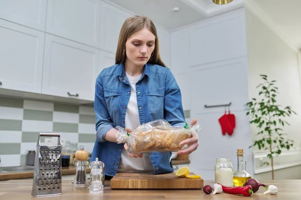 Молодая женщина готовит курицу в рукаве для выпечки со специями — стоковое фото