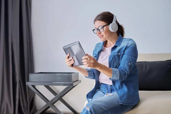 Talking woman in headphones looking into digital tablet webcam — Stock Photo, Image