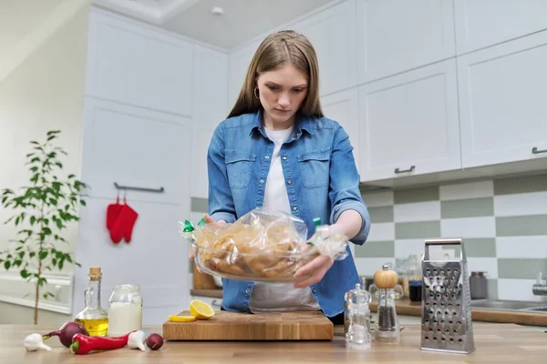 Ung kvinna matlagning bakad kyckling i bakning ärm med kryddor — Stockfoto