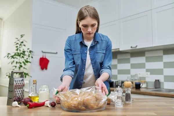 Giovane donna che cucina pollo al forno in manica di cottura con spezie — Foto Stock