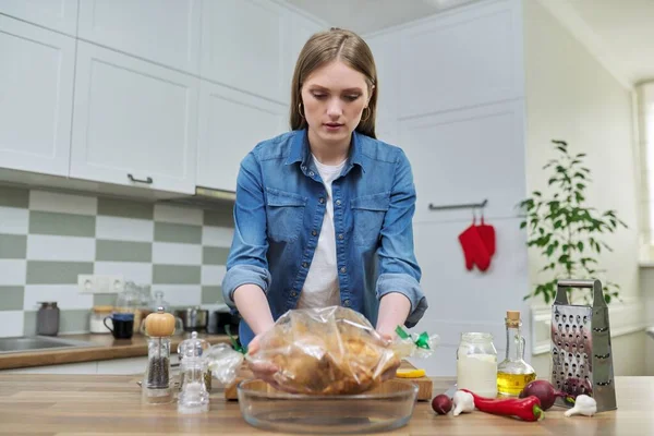 Молодая женщина готовит курицу в рукаве для выпечки со специями — стоковое фото