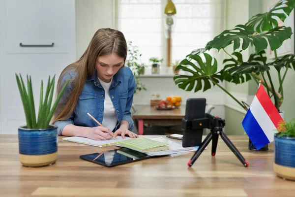 Mujer estudiante sentada en casa estudiando en línea, mirando webcam smartphone —  Fotos de Stock