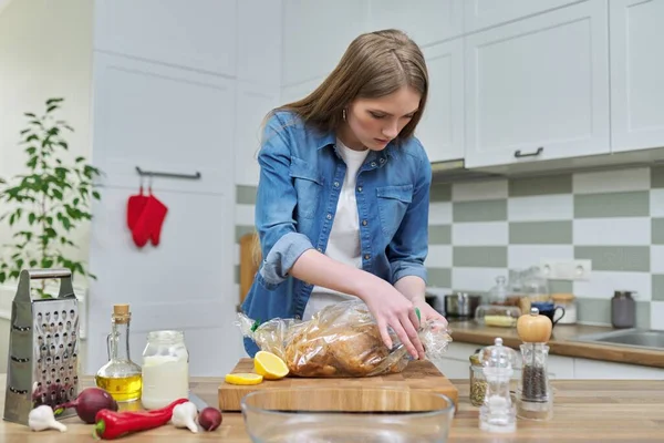 Ung kvinna matlagning bakad kyckling i bakning ärm med kryddor — Stockfoto