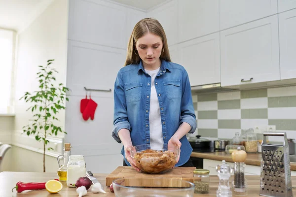 Ung kvinna förbereder kyckling hemma, kök interiör bakgrund — Stockfoto