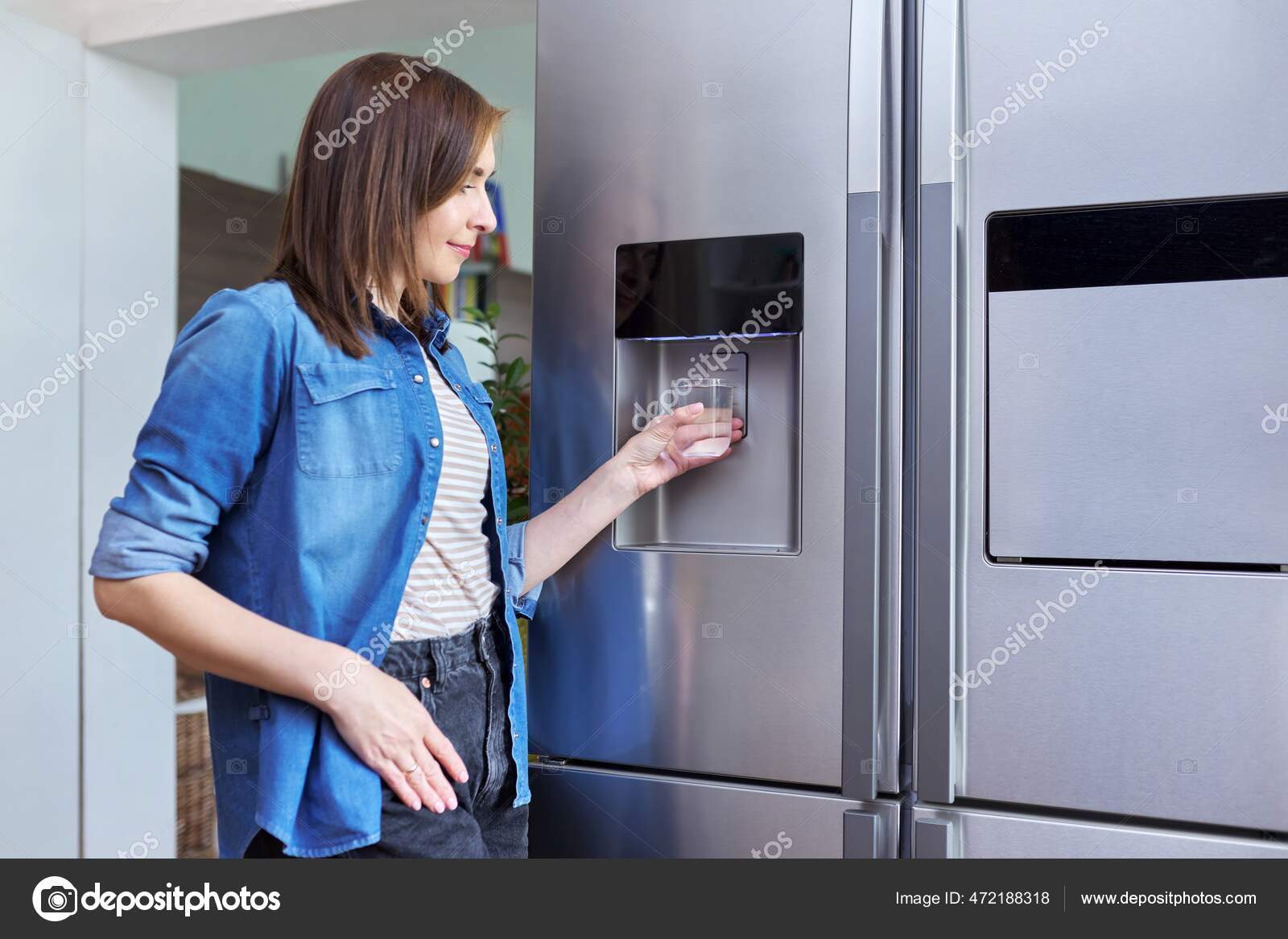 Water dispenser, woman taking cold water into glass from home