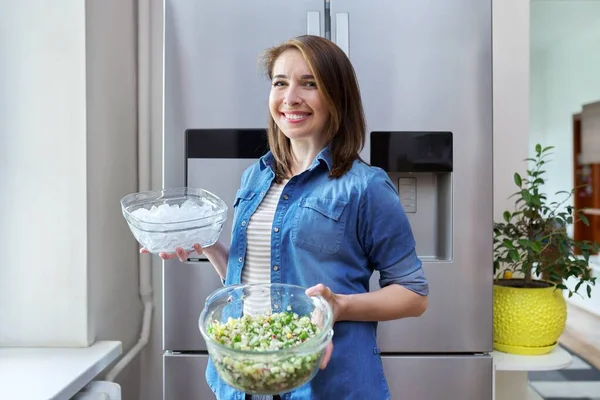 Усміхнена жінка з чашею льоду і тарілкою овочевого салату в руках — стокове фото