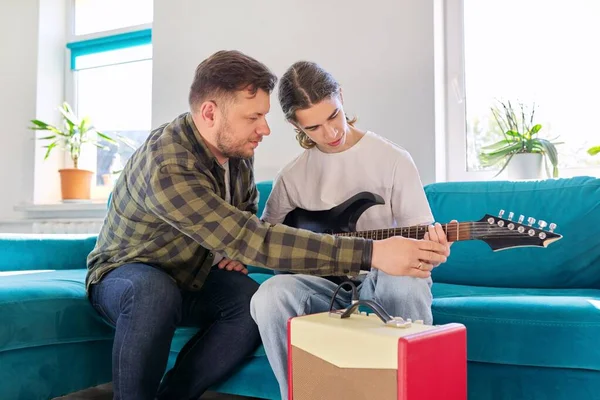 Pai ensina seu filho adolescente a tocar guitarra elétrica — Fotografia de Stock
