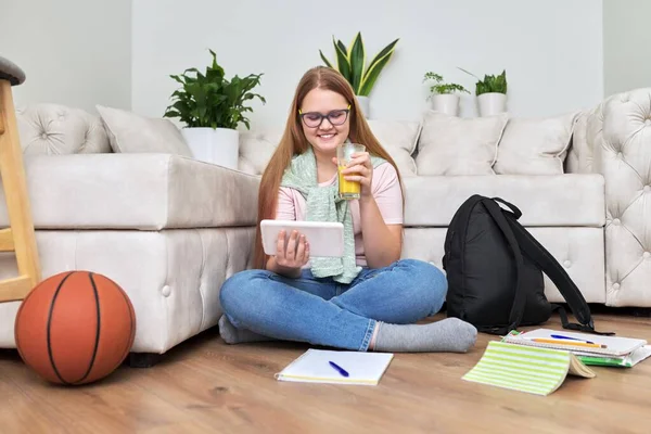 Ragazza adolescente seduta a casa sul pavimento guardando lo schermo del tablet digitale — Foto Stock