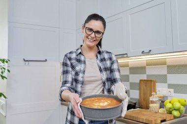 Mutfakta gülümseyen kadın yeni pişmiş turtayla eldiven.