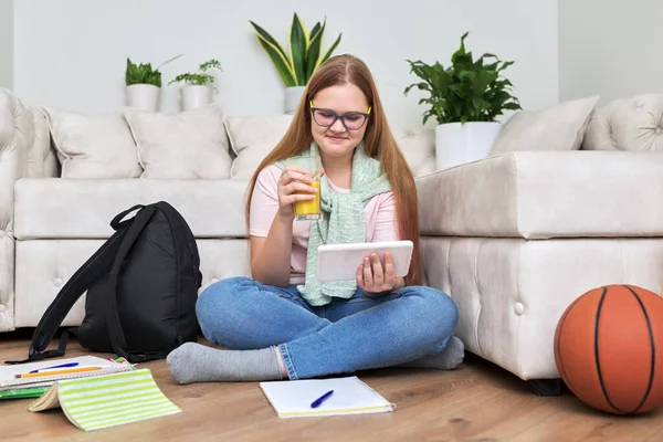 Ragazza adolescente seduta a casa sul pavimento guardando lo schermo del tablet digitale — Foto Stock