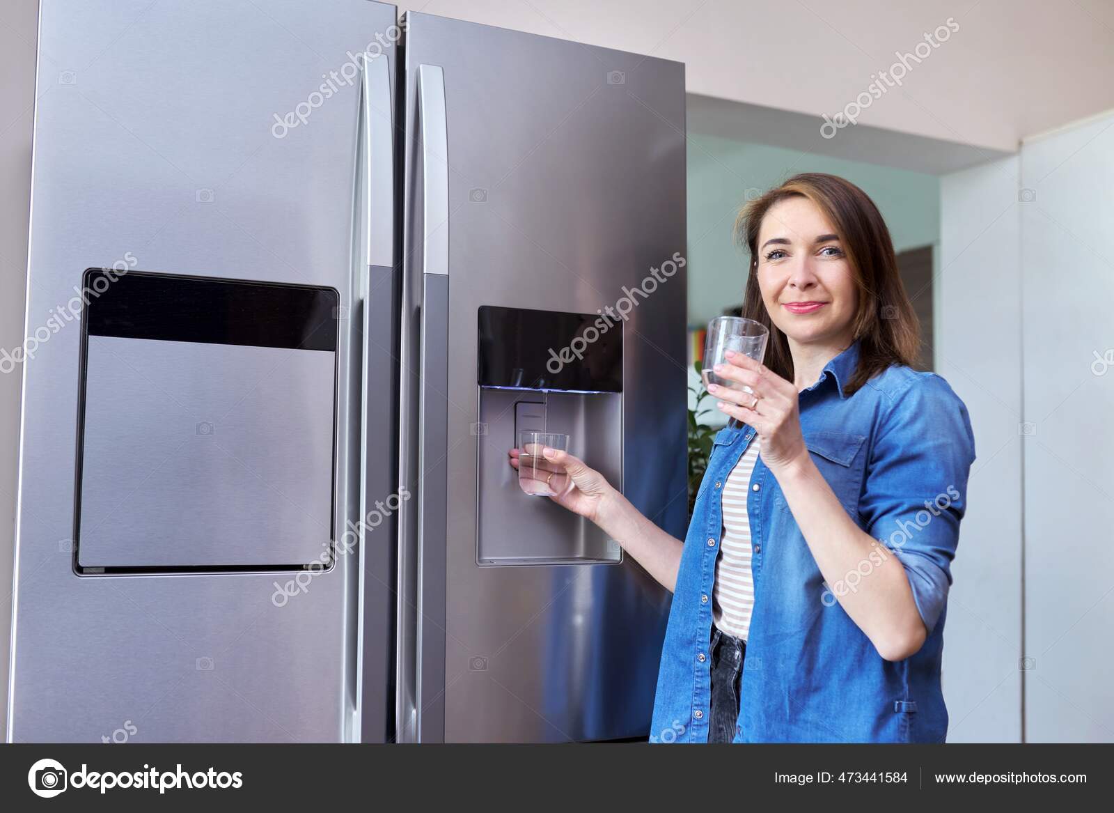 Dispensador de agua, mujer que toma agua fría en el vidrio del