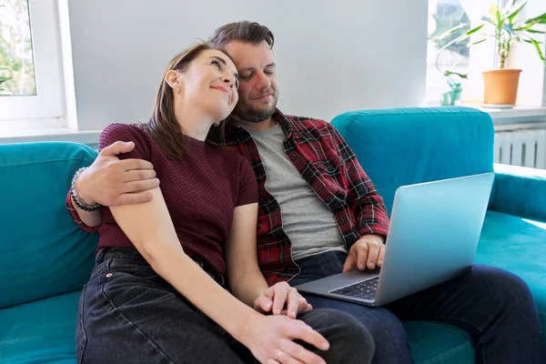 Feliz casal de meia-idade sentado no sofá com laptop — Fotografia de Stock