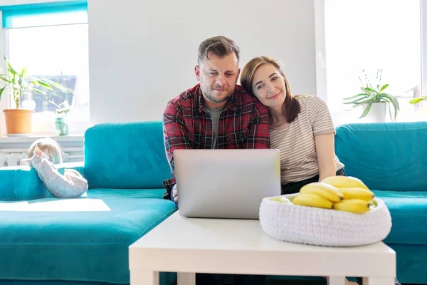 Sorrindo rindo casal positivo 40 anos, marido e mulher olhando para laptop — Fotografia de Stock