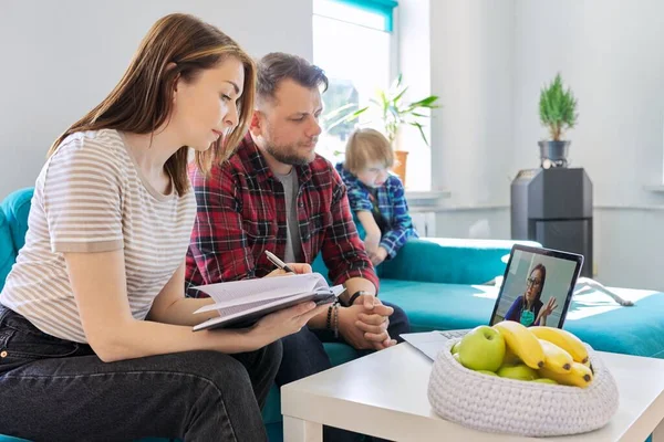 Consulta médica on-line, família sentada em casa no sofá na sala de estar com laptop — Fotografia de Stock