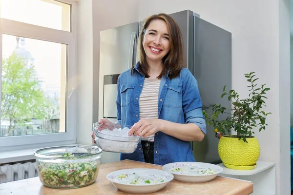 Усміхнена жінка на кухні біля холодильника з льодом для охолодження їжі — стокове фото