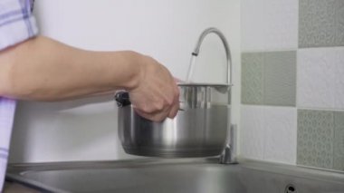 Yemek pişirmek için tencereyle yakın plan filtrelenmiş musluk suyu al.