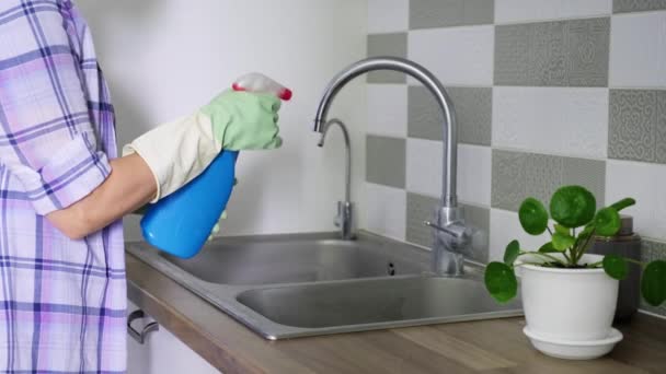 Vrouw schoonmaken dubbel chroom spoelbak in rubber handschoenen met behulp van spray en spons — Stockvideo